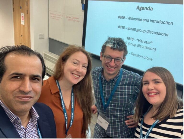 A group of four people in front of a presentation screen